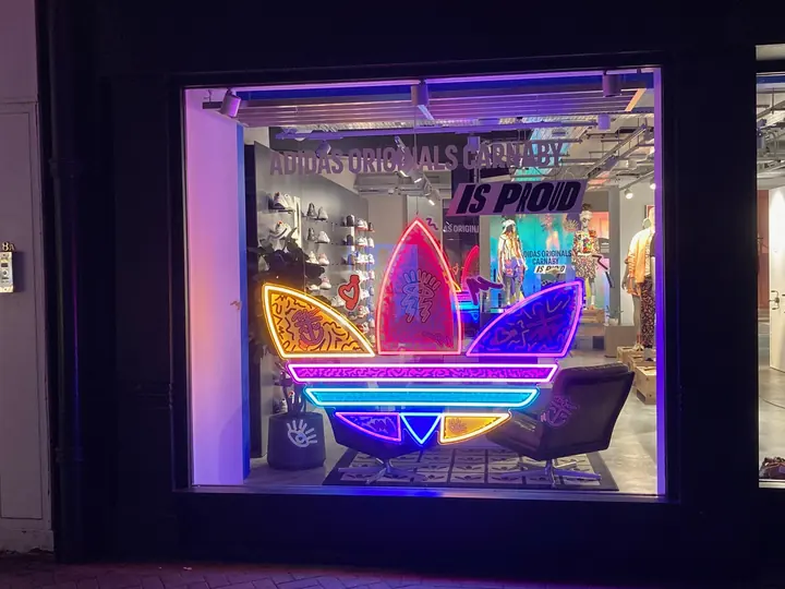 Adidas Originals window installation with neon trefoil and printed graphics