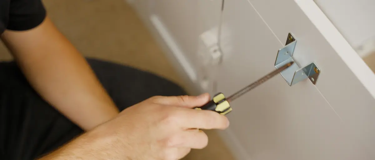 Installer fixing a retail shelf component with a screwdriver