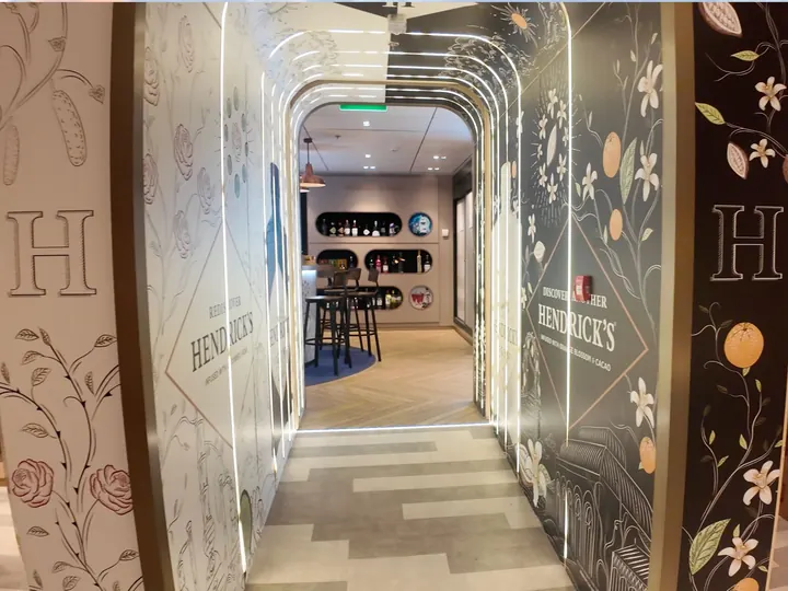 Hendrick's gin branded walkway with floral wall graphics installed in a travel retail space